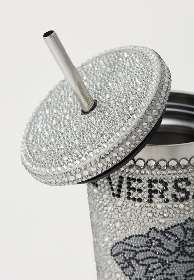 Silver drink container with metallic straw, covered in rhinestones. Features embossed text and a black rubber sealing ring for the lid.