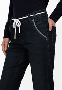 Pantalones de mezclilla azul marino con un cordón blanco, que cuentan con bolsillos laterales, un diseño clásico de cinco bolsillos y detalles de costura clara.