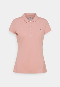 Damska koszulka polo z krótkim rękawem w kolorze przykurzonego różu z kołnierzykiem, pięcioma białymi guzikami i małym logo Tommy Hilfiger po lewej stronie klatki piersiowej.