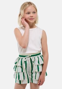 Haut sans manches blanc associé à un short rayé vert et blanc avec un design à volants, une taille élastique et une garniture décorative.