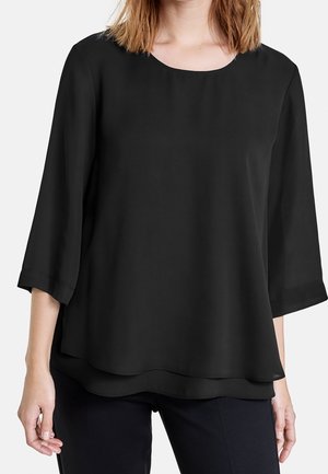 Czarna, zwiewna bluzka z rękawami do połowy przedramienia, okrągłym dekoltem i warstwowym dołem. Wykonana z miękkiego, lekkiego materiału, odpowiednia do noszenia na warstwach.