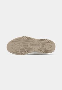 Súťaž béžovej Reebok tenisky s textúrovanými úchopmi, obehovými vzormi a logom Reebok v strede.