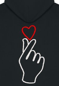 Il hoodie nero presenta un gesto della mano ricamato in bianco con un cuore rosso sopra. Il design è audace e grafico, enfatizzando il contrasto.