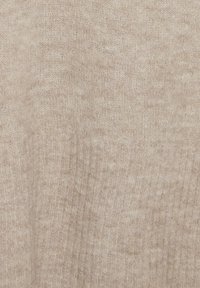 Tissu tricoté beige clair avec une texture douce. Subtiles variations de couleur et un motif à côtes fines sur l'ensemble du matériau.