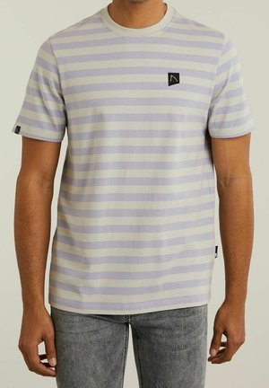 Hombre con camiseta de manga corta, en rayas horizontales lavanda y blanco, con pequeños logotipos negros en el pecho y los puños de las mangas.