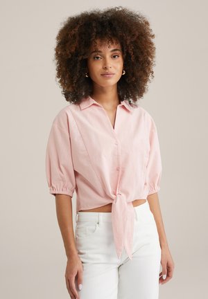 Short-sleeve, light pink button-up shirt with a tie at the waist. Features gathered sleeves and a relaxed fit, made of soft fabric.