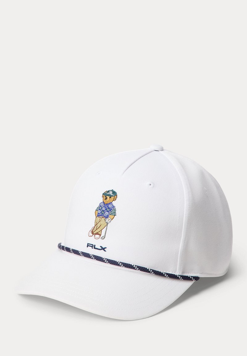 Hvit baseballcaps med brodert teddybjørn iført golfklær og holder en golfkølle, og en marineblå mønstret kant over bremmen.