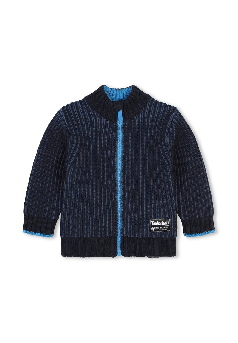 Cardigan lavorato a maglia blu navy con righe verticali, colletto blu e dettagli con zip, e logo Timberland in basso a destra. Texture morbida.