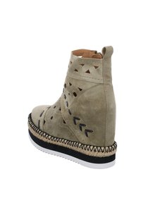 Botín de ante beige con patrones geométricos troquelados. Cuenta con una plataforma estilo espadrille tejida y una suela de goma negra con borde blanco.