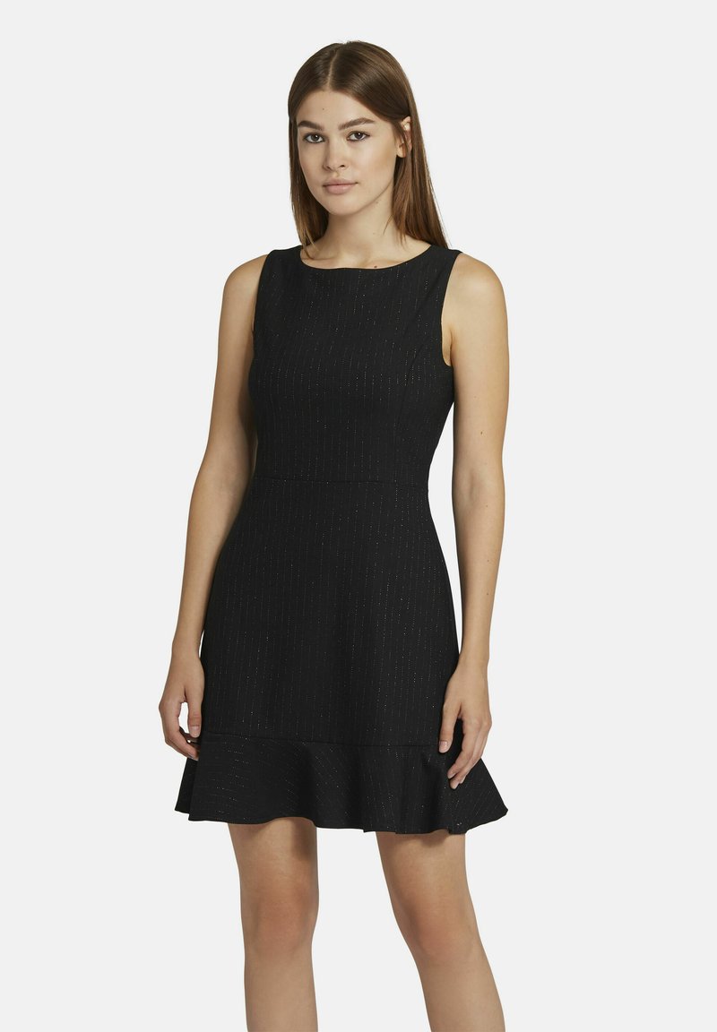 Schwarzes ärmelloses Kleid mit einem figurbetonten Oberteil, ausgestelltem Rüschensaum und dezenten strukturierten Streifen. Glatter Stoff mit einem leichten Glanz.