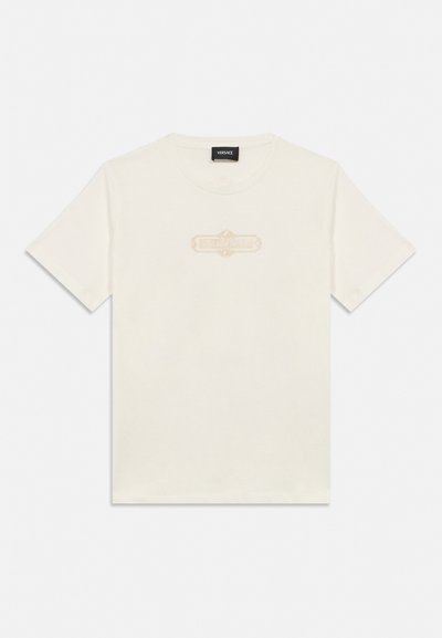 T-shirt blanc à manches courtes et col rond avec un logo beige subtil et un design Versace centré sur la poitrine.
