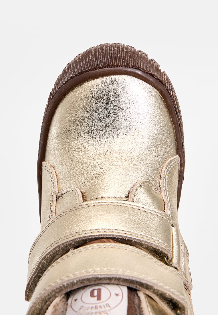 Goldfarbene metallische Schuh mit glatter Oberfläche, runder Zehenpartie und braunem Gummisohle. Verfügt über einen Klettverschluss und genähte Details.