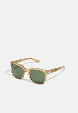 Óculos de sol quadrados com uma armação translúcida em bege, lentes com tonalidade verde e detalhes em padrão nas hastes. Elementos de design distintivos incluem hardware brilhante.