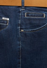 Donkerblauwe denim jeans achter met twee zakken, beige stiksels en een metalen "MEYER" merklabel op de linkerkant van de zak.
