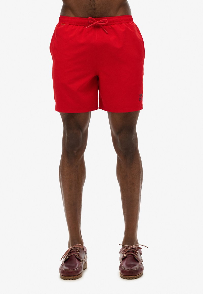 Bañador rojo con cintura elástica y cordón, con una textura suave y un pequeño logo en el lado inferior.