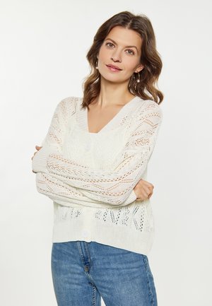 Bílé pletené kardigan s texturovaným, otevřeným krajkovým vzorem. Má výstřih do V, dlouhé rukávy a zapínání na knoflíky vpředu.
