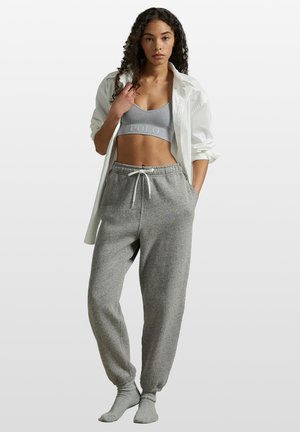 Graue Jogginghosen mit elastischen Bündchen, Kordelzugbund und passendem grauem Sport-BH. Weißes oversized Hemd darüber getragen.