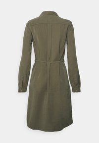 Vestito verde oliva con maniche lunghe, polsini a bottone, colletto aperto, vita con cintura e dettaglio di piega sul retro, realizzato in un morbido tessuto testurizzato.