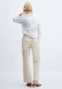 White long-sleeve shirt, loose fit, with a back seam detail; beige cargo pants with side and back pockets; minimalist design, smooth texture.