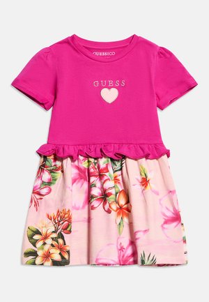 Ροζ φόρεμα με κοντά μανίκια, με την επιγραφή «GUESS» και καρδιά στο πάνω μέρος, ζώνη με βολάν και φούστα με μοτίβο λουλουδιών με τροπικά άνθη.