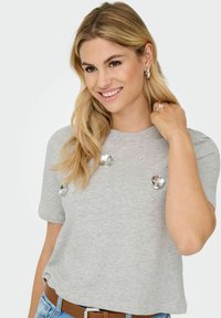 T-shirt grigio a maniche corte realizzato in tessuto morbido, con decorazioni floreali argentate e piccoli gioielli sul davanti, vestibilità rilassata.