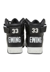 Baskets montantes noires avec des accents blancs, dotées d'une semelle épaisse, en cuir texturé et avec une marquage "Ewing" et "33" bien visible sur le talon.