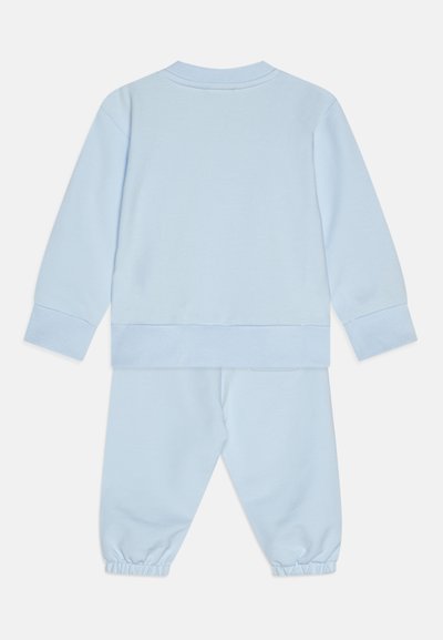 Ανοιχτό μπλε σετ φούτερ και παντελόνι, φτιαγμένο από μαλακό βαμβάκι. Μπλουζάκι με στρογγυλή λαιμόκοψη, ελαστικοί καρποί στα μανίκια και τα παντελόνια, ελάχιστες λεπτομέρειες.