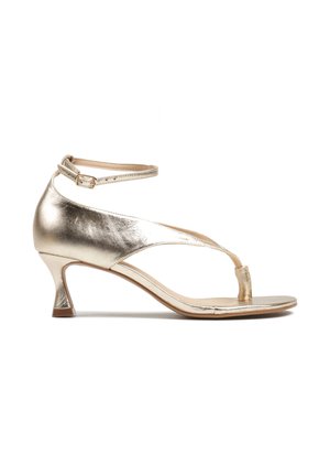 Metaliczne złote sandały z odkrytymi palcami, cienkim paskiem przy kostce, pętelką na palce oraz niskim, zakrzywionym obcasem na białym tle.