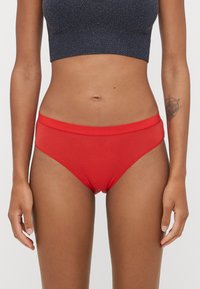 Czerwone bawełniane majtki bikini z gładkim pasem i minimalnym szyciem. Charakteryzują się klasycznym krojem z wysokim wycięciem nogawek i miękką teksturą.