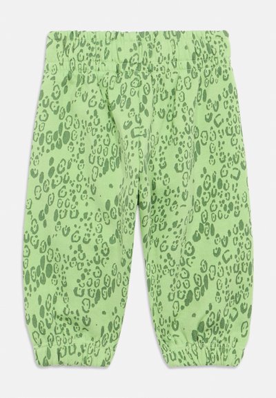 Roheline leopardimustriga püksid, mis on valmistatud pehmest materjalist, elastse vöökoha ja kogutud pahkluude olemasoluga. Kõigis osades eristuv täppide muster.