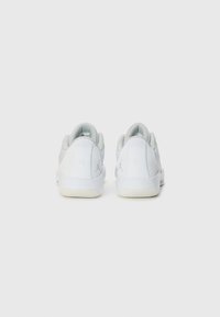 White athletic shoes with a textured mesh upper, cushioned heel, and rubber outsole. Features a discreet logo on the heel.