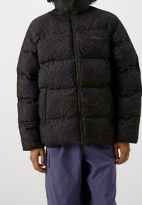 Giacca a vento trapuntata di colore blu scuro con motivo paisley, dotata di un colletto alto e zip a lunghezza completa, realizzata in materiale isolante.