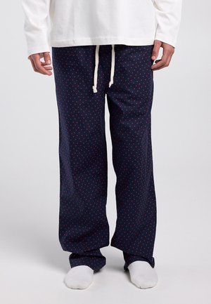 Marineblauwe pyjamabroek met kleine rode hartjes, gemaakt van zacht stof, met een elastische tailleband en trekkoord voor een verstelbare pasvorm.