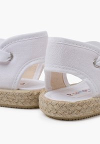 Sandali bianchi in tela con suola in juta intrecciata, design aperto e cinturini elasticizzati alla caviglia. Presentano un interno in tessuto morbido e un dettaglio con logo.