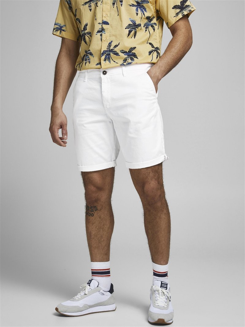 Witte denim shorts met een rechte snit, voorzien van een sluiting met knopen aan de voorkant. Gecombineerd met een kortebloemige gele shirt met palmenpatroon en sneakers.