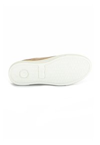 Bruine suède sneaker met een getextureerde witte rubberen zool, voorzien van een rond logo en een visgraatpatroon voor grip.