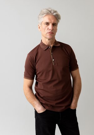 Bruine poloshirt met een kraag, korte mouwen en een drieknopenlijst. Heeft contrasterende biezen op de kraag en mouwen.