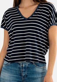 Camiseta de rayas marinas con rayas horizontales blancas, escote en V con un ribete texturizado similar al denim, mangas cortas, ajuste relajado.