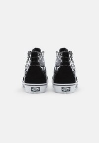 Czarne sneakersy typu high-top z wierzchem z wzorzystej tkaniny, zamszowymi akcentami i białą gumową podeszwą. Charakteryzują się kontrastującym przeszyciem i logo na pięcie.