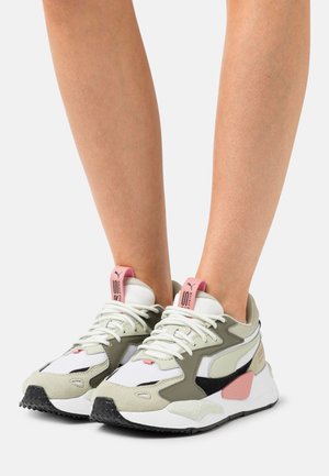 Scarpe sportive con una combinazione di grigio chiaro, verde oliva, bianco e nero. Caratterizzate da materiali testurizzati, lacci prominenti e un accento rosa sul tallone.