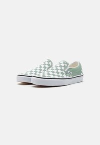 Gröna och vita rutiga slip-on skor med en ovandel av canvas, gummisula och minimal hårdvara, med en lågprofil design och vadderad krage.