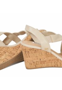 Beige sleehakken met een gestructureerde kurken hak, leren kruisriemontwerp en gouden accenten. Gladde voetbed met een rubberen zool.