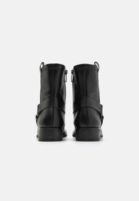 Botas negras de piel hasta el tobillo con un acabado suave, que presentan un detalle de correa con botones a presión y un tacón bajo de madera.