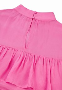 Vaaleanpunainen sifonkipaita, jossa on röyhelöhelma, takana avaus avaimenreikälukolla ja kaksinkertainen nappikiinnitys, sekä sileä ja kevyt rakenne.