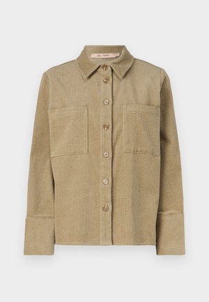 Beežist köndernahk-särk-jope nupuga ees, kaks rinna-taskut ja krae. Omab tekstureeritud ribakujundust ja ümberpööratud pikki varrukaid.