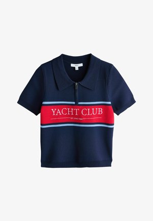 Granatowa koszulka polo z krótkim rękawem, zapinana z przodu na zamek, z czerwoną poziomą linią na wysokości klatki piersiowej z napisem "Yacht Club Est. Since 1989."