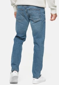 Lichtblauwe denim jeans met een rechte pijp, voorzien van twee achterzakken, subtiele textuur en afgewerkt met een opgerolde zoom.