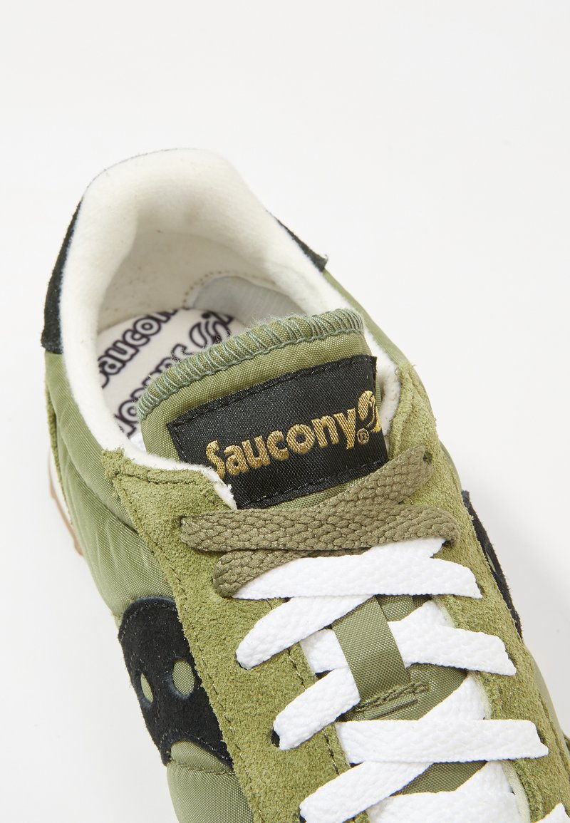 Groene sneakers van een mix van nylon en suède materialen. Heeft witte veters, zwarte accenten en een gouden logo op de tong. Geweven details.