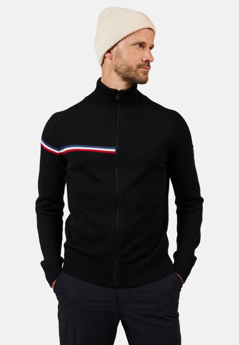 Sudadera negra con cremallera y cuello alto, que presenta rayas horizontales rojas, blancas y azules en el pecho, así como puños y dobladillo de canalé.