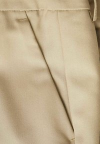 Tissu beige présentant une texture lisse avec un tissage diagonal subtil. Comprend des plis nets et une apparence épurée et soignée.